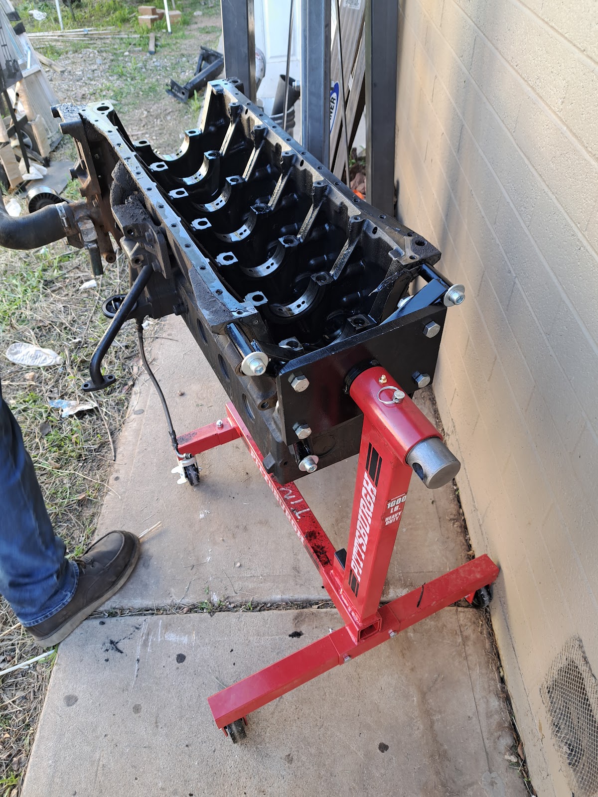 Inline-six engine block stripped bare and bolted to a red heavy-duty engine stand